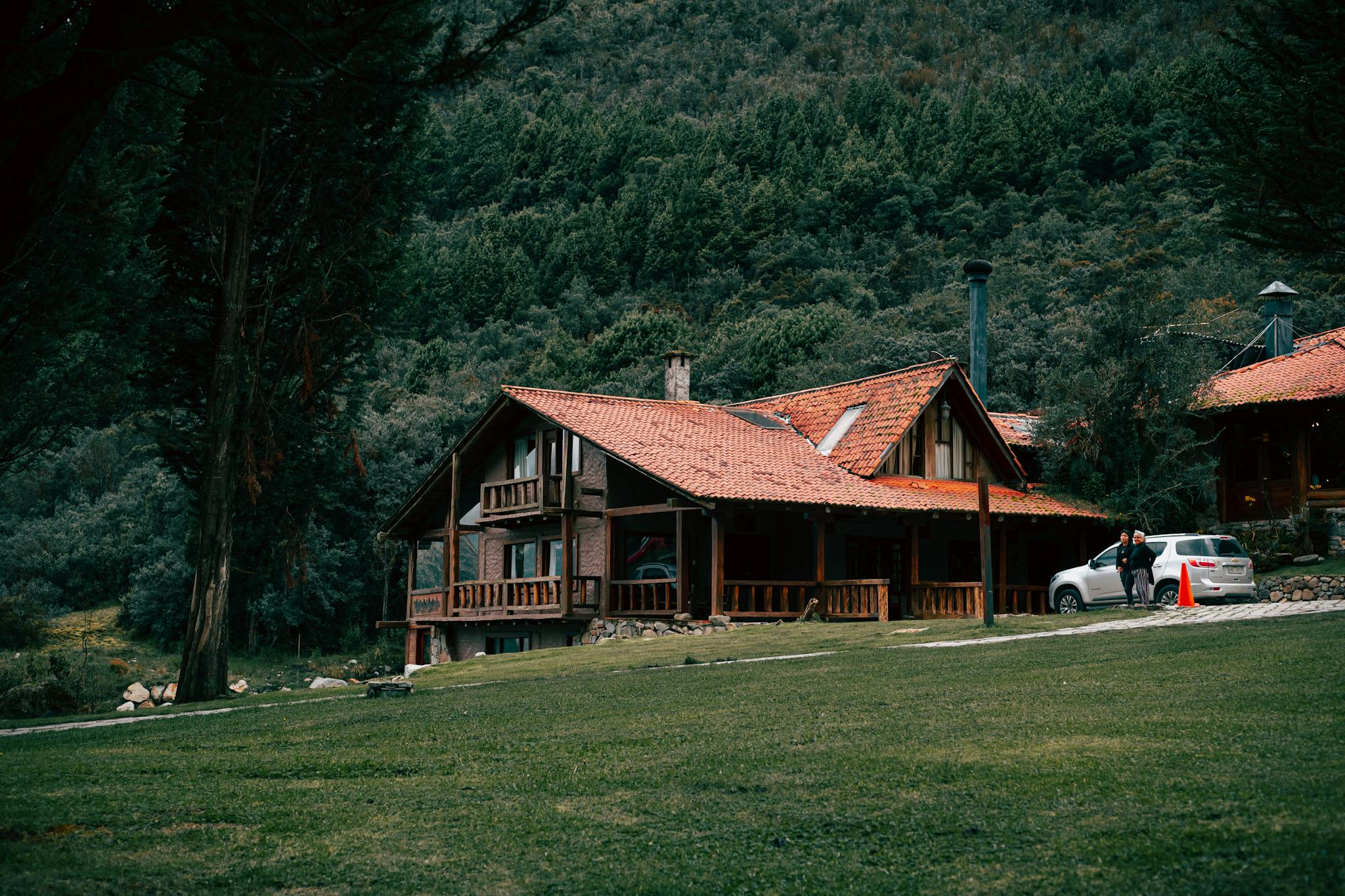 A picturesque wooden lodge surrounded by lush forest and mountains, perfect for a serene retreat.